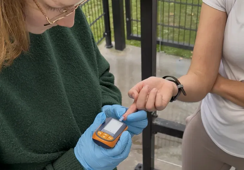 Margaux meet de lactaatwaarde met een druppel bloed uit de vinger van een sporter