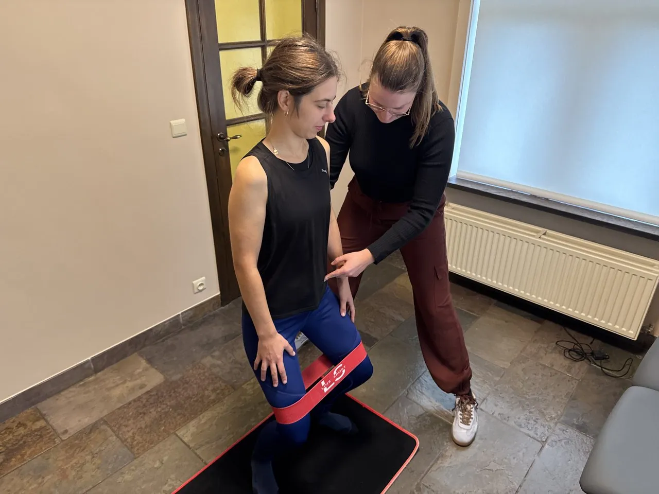 Margaux begeleidt een patiënt bij een oefening met een weerstandsband